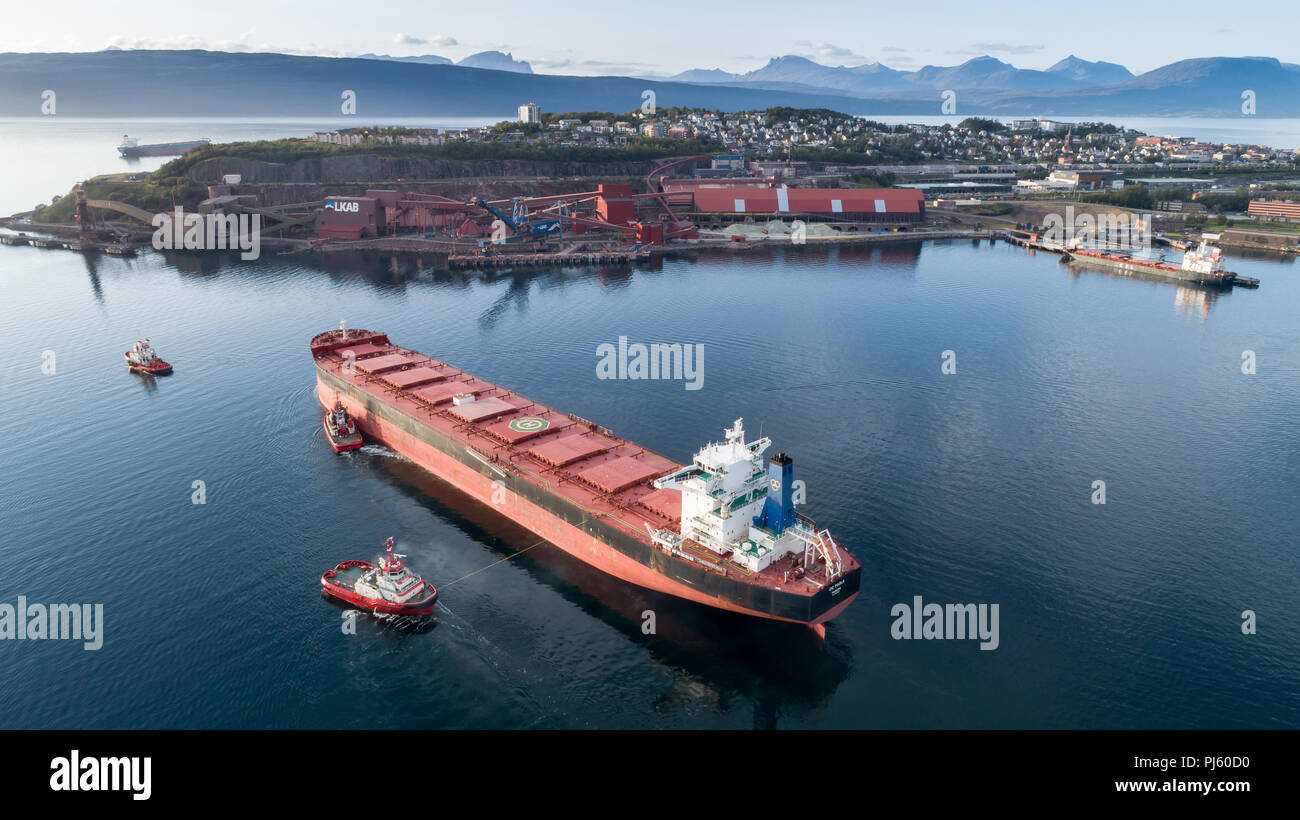 Norvegia,NARVIK - 1 settembre 2018:ripresa aerea di una nave cargo avvicinando LKAB terminal portuale con l aiuto della nave di rimorchio, Narvik, Norvegia Foto Stock