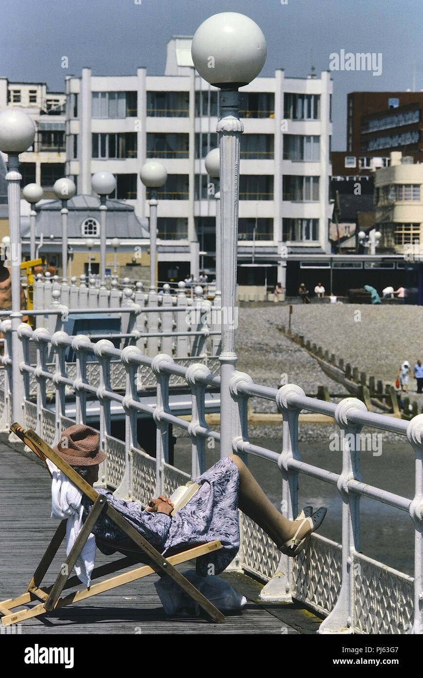 Donna anziana dorme in una sedia a sdraio su Worthing pier, West Sussex, in Inghilterra, Regno Unito. Circa ottanta Foto Stock