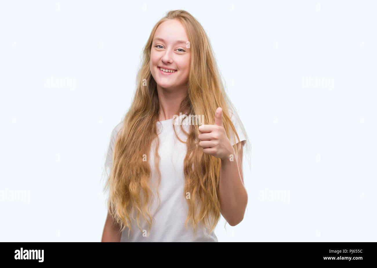 Adolescente bionda donna felice con un grande sorriso facendo segno ok, pollice in alto con le dita, segno eccellente Foto Stock