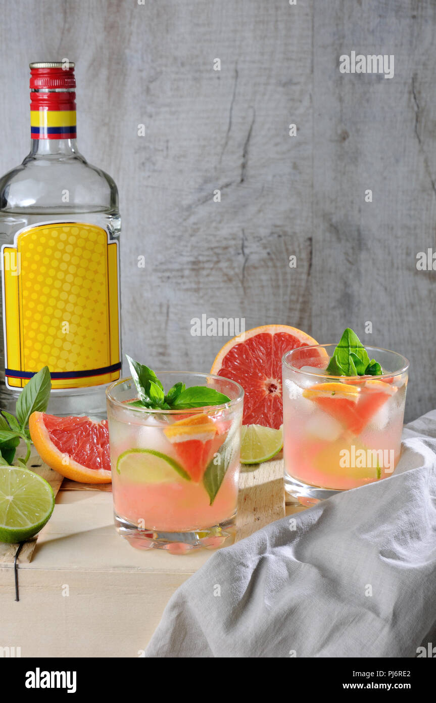 Cocktail da London dry gin con succo da spremuta di pompelmo rosso e foglie di basilico delicato del limone, fettine di lime e refrigerate di cubetti di ghiaccio. Foto Stock