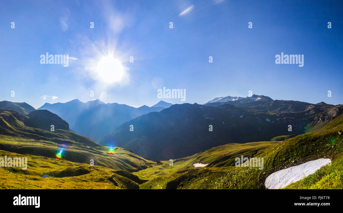 Raggi solari del mattino su una lunga valle nebuloso, visto da Alti Tauri e la neve rimane nel mid di estate Foto Stock