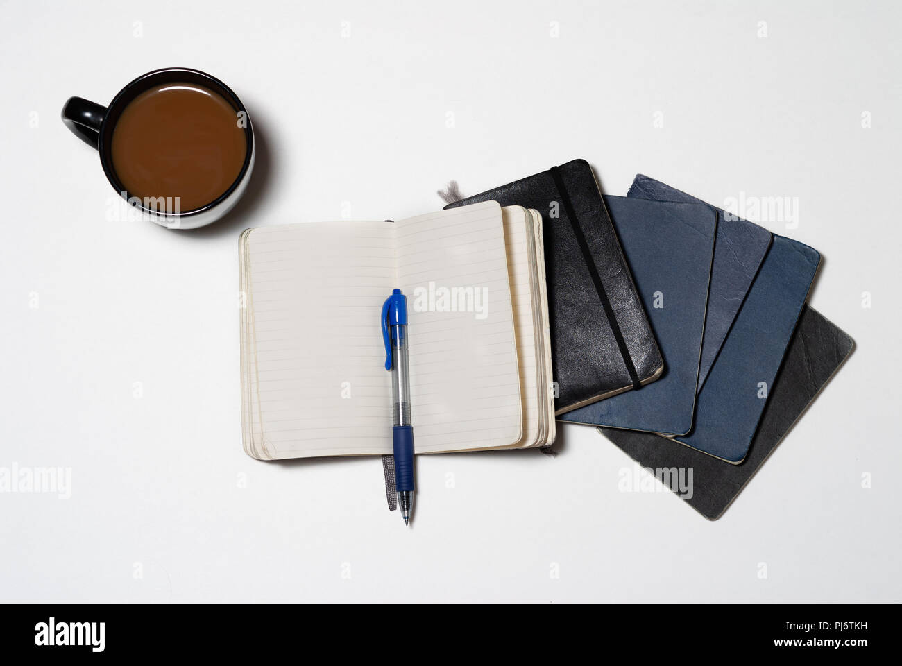 Impilati isolato usurati riviste per notebook con penna e caffè Foto Stock