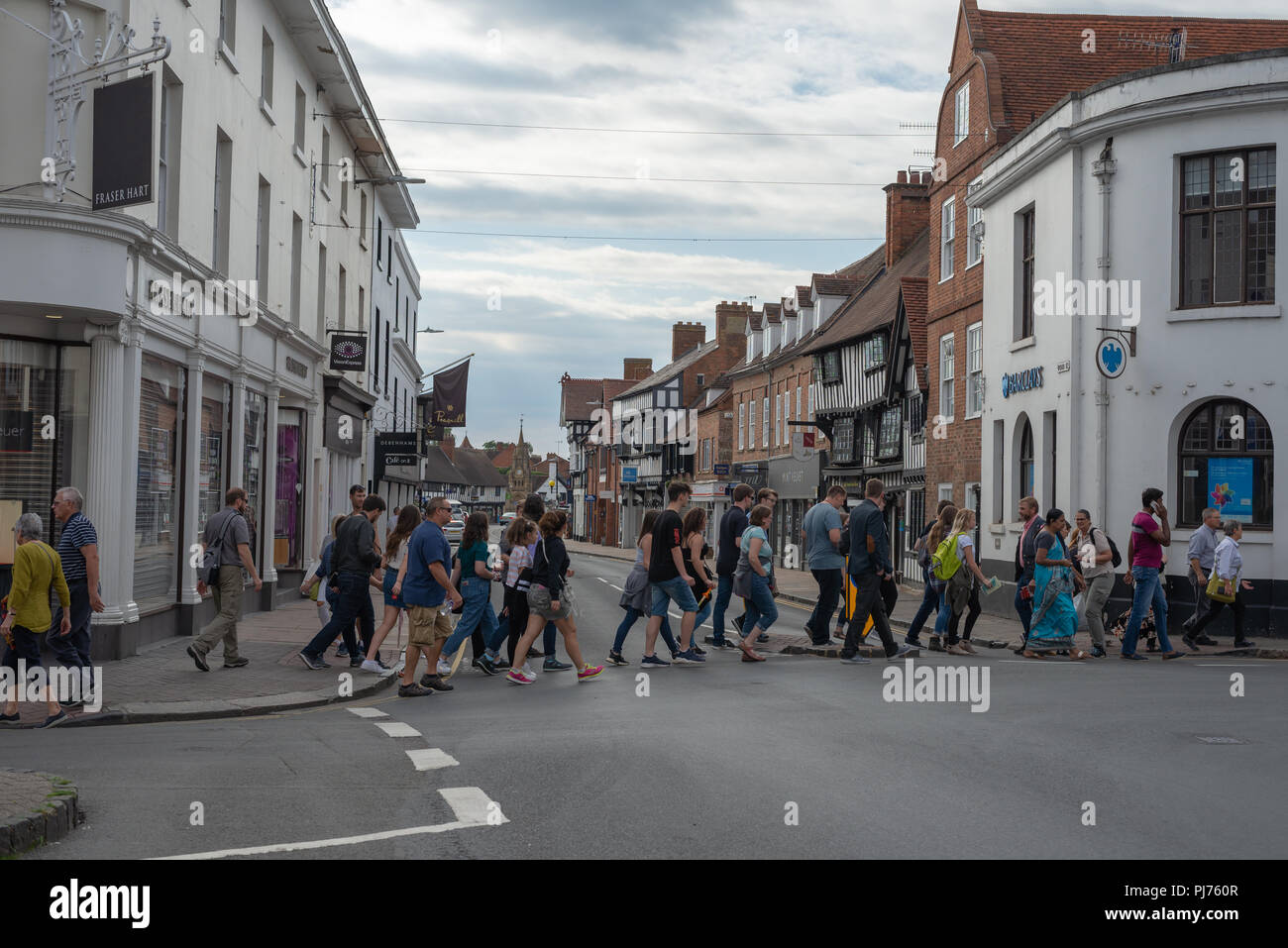 Un gruppo di turisti attraversando una strada in Stratford Upon Avon, Warwickshire, Inghilterra Foto Stock