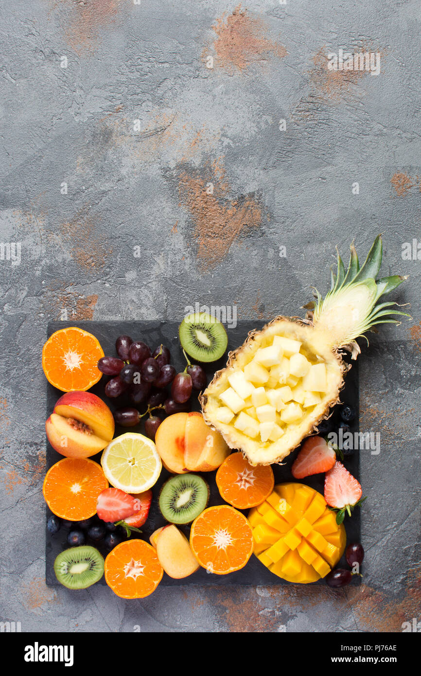 Foto verticale di tagliare la frutta e bacche piatto sulla pietra grigia sfondo, copia spazio, vista dall'alto, il fuoco selettivo Foto Stock