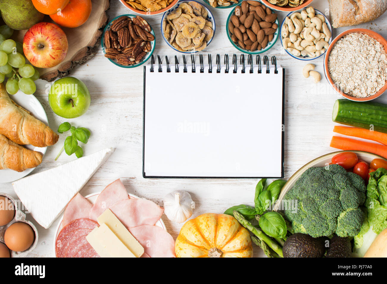 Varietà di frutta e verdura, noci, cereali, prosciutto, formaggio sul bianco tavolo in legno, vista dall'alto, selecitve focus Foto Stock