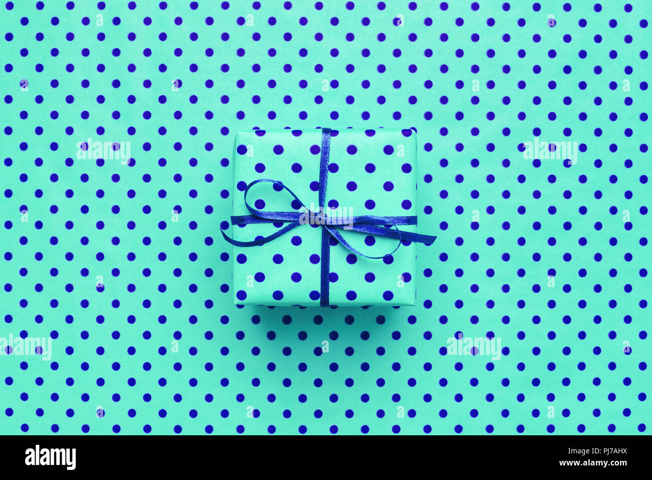 Confezione regalo su turchese carta di avvolgimento con il blu a pois. Design minimale neon di sfondo per scheda, flyer, invito, cartellone. Foto Stock