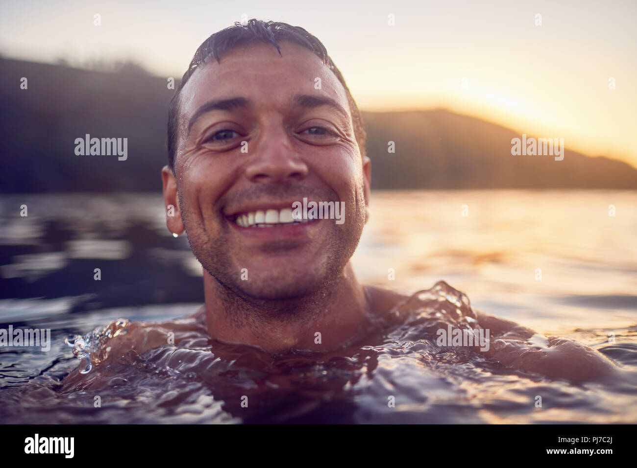 Close up ritratto sorridente e spensierato uomo nuotare nell'oceano Foto Stock