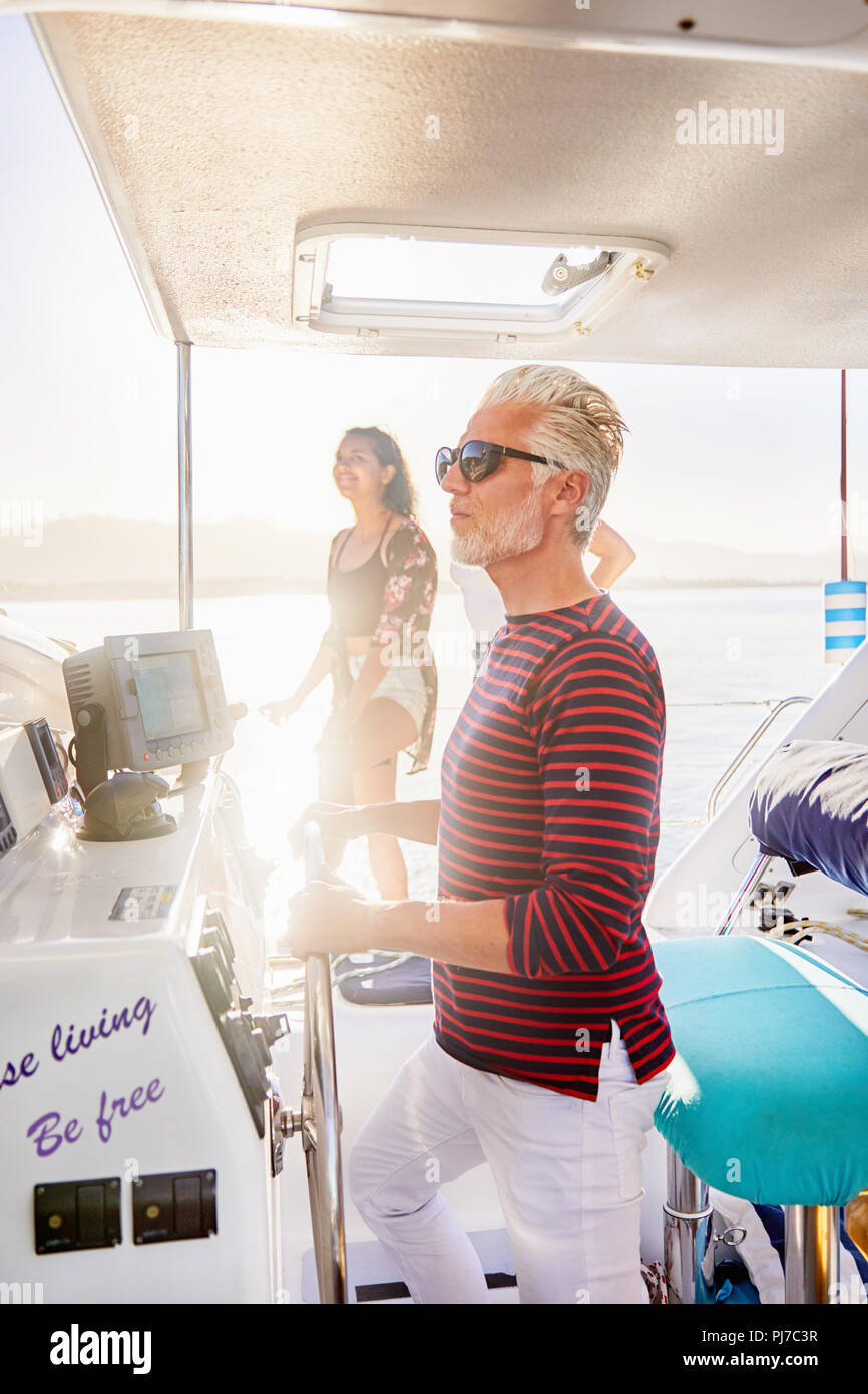 Uomo al timone sulla barca di sole Foto Stock