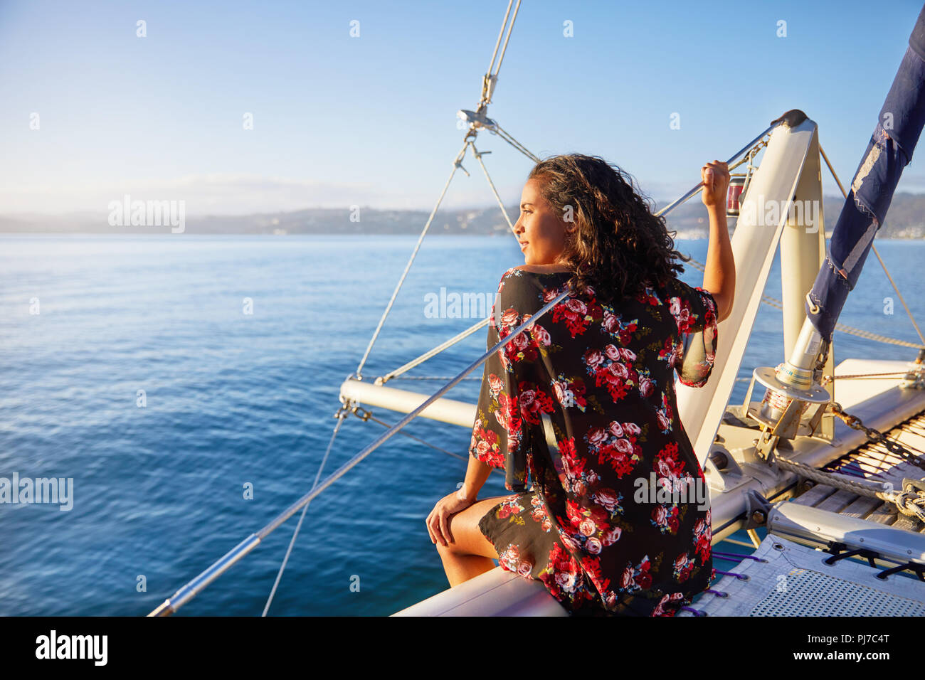 Serena giovane donna rilassante sul catamarano soleggiato, guardando a blu oceano Foto Stock