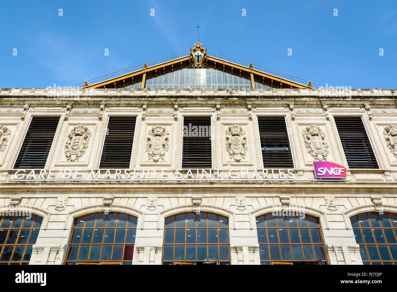 La facciata della stazione di Saint-Charles a Marsiglia, in Francia con il nome della stazione e il logo SNCF sotto gli stemmi delle città servite. Foto Stock