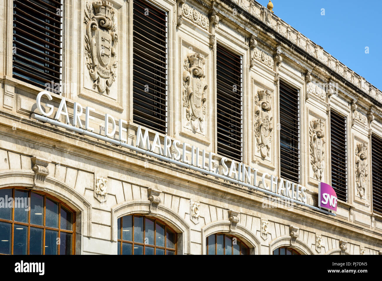 La facciata della stazione di Saint-Charles a Marsiglia, in Francia con il nome della stazione e il logo SNCF sotto gli stemmi delle città servite. Foto Stock