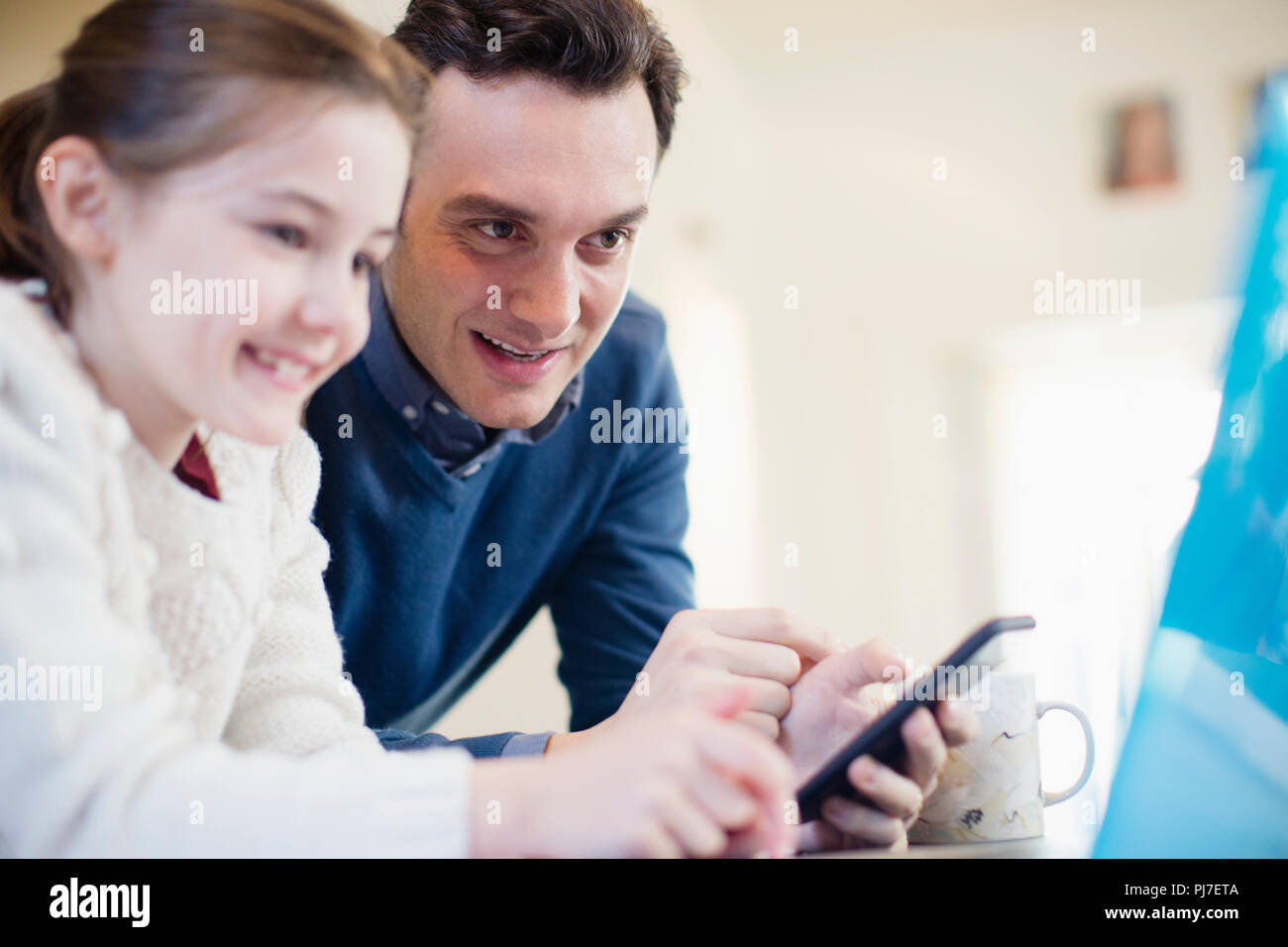 Padre con smart phone utilizzando computer portatile con la figlia Foto Stock