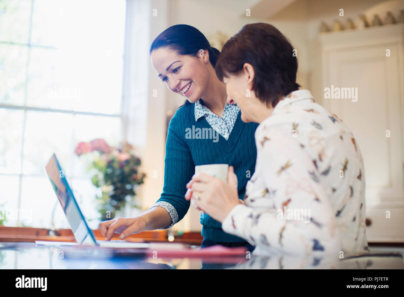 La figlia e la madre senior utilizzando laptop in cucina Foto Stock