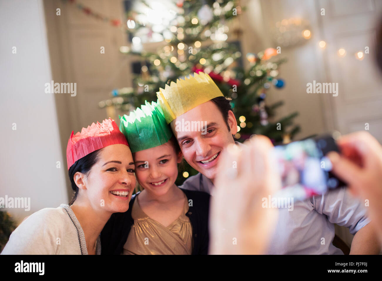 La famiglia felice in corone di carta che posano per una foto di Natale in salotto Foto Stock