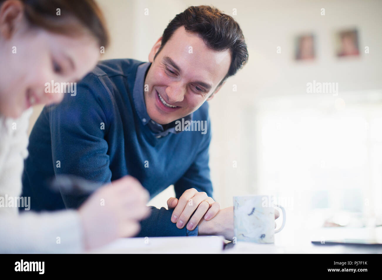 Padre sorridente aiutando la figlia con i compiti Foto Stock