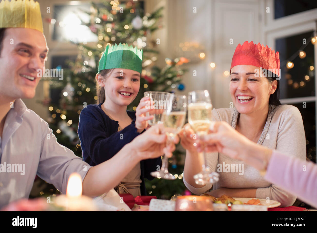 La famiglia felice in carta corvi acqua di tostatura e bicchieri di champagne a cena di Natale Foto Stock