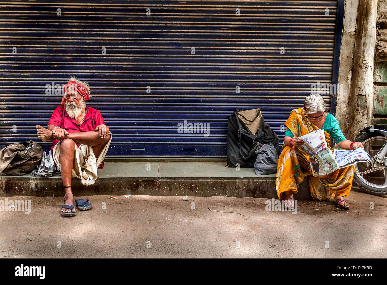 Senior Citizen donna leggendo il giornale e senior citizen uomo seduto vicino a Foto Stock