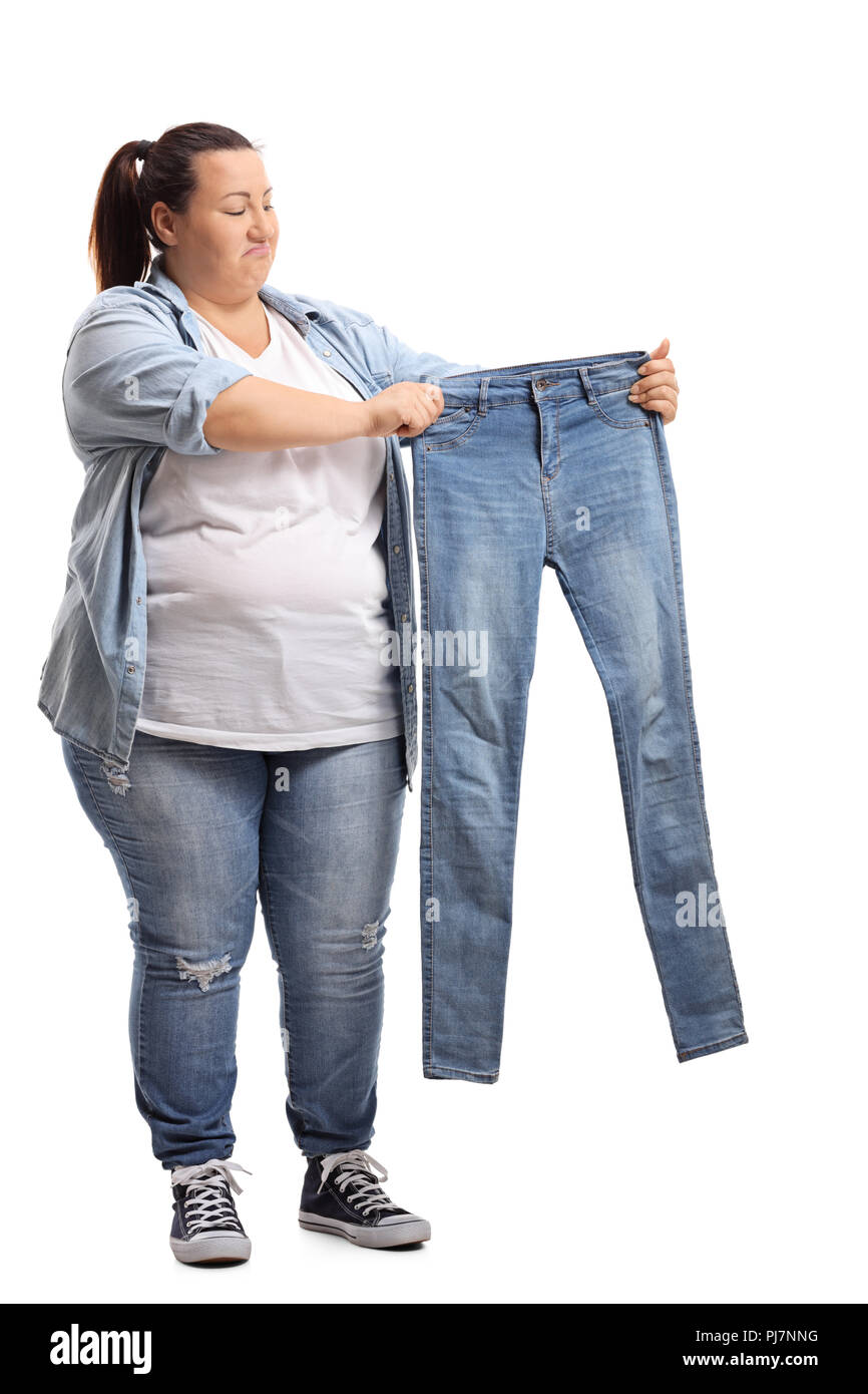 A piena lunghezza Ritratto di una donna sovrappeso tenendo un paio di jeans piccoli isolati su sfondo bianco Foto Stock