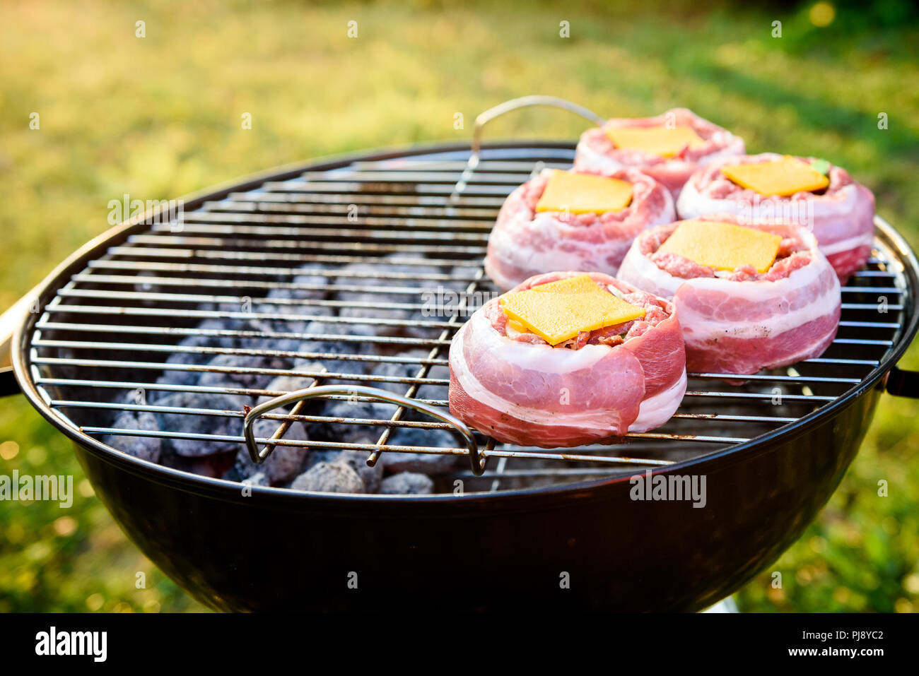 Rendendo fatta in casa birra può Bacon gli hamburger sul grill barbecue. La preparazione di polpette ripiene, avvolto in pancetta e grigliare sul calore indiretta nella natura a bac Foto Stock
