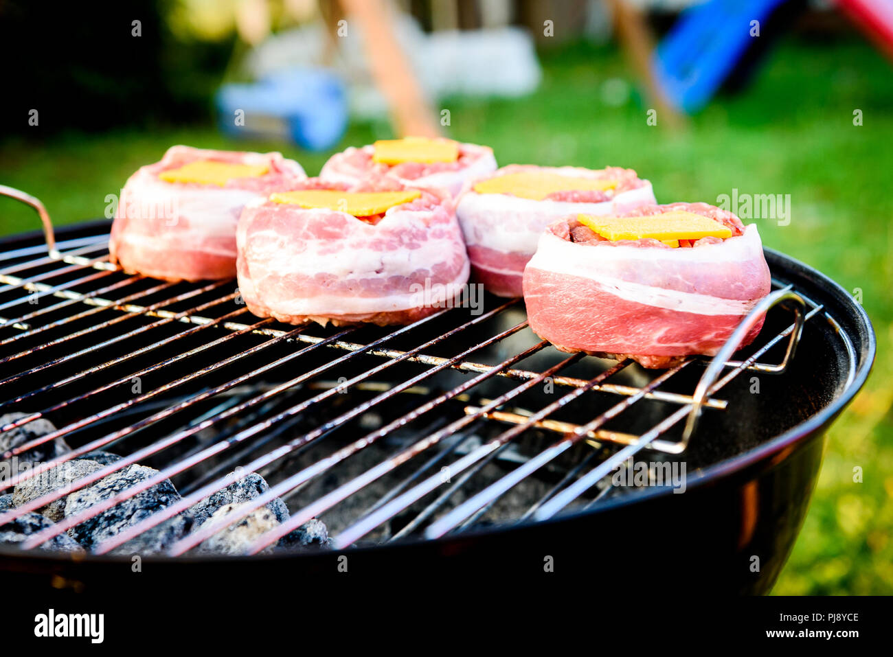 Rendendo fatta in casa birra può Bacon gli hamburger sul grill barbecue. La preparazione di polpette ripiene, avvolto in pancetta e grigliare sul calore indiretta nella natura a bac Foto Stock