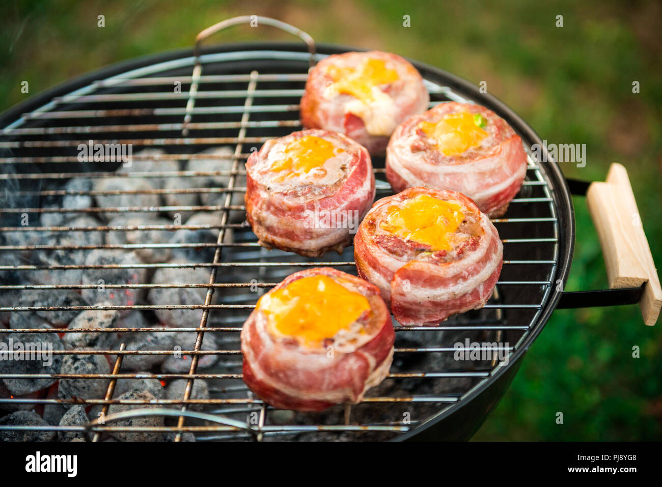 Rendendo fatta in casa birra può Bacon gli hamburger sul grill barbecue. La preparazione di polpette ripiene, avvolto in pancetta e grigliare sul calore indiretta nella natura a bac Foto Stock