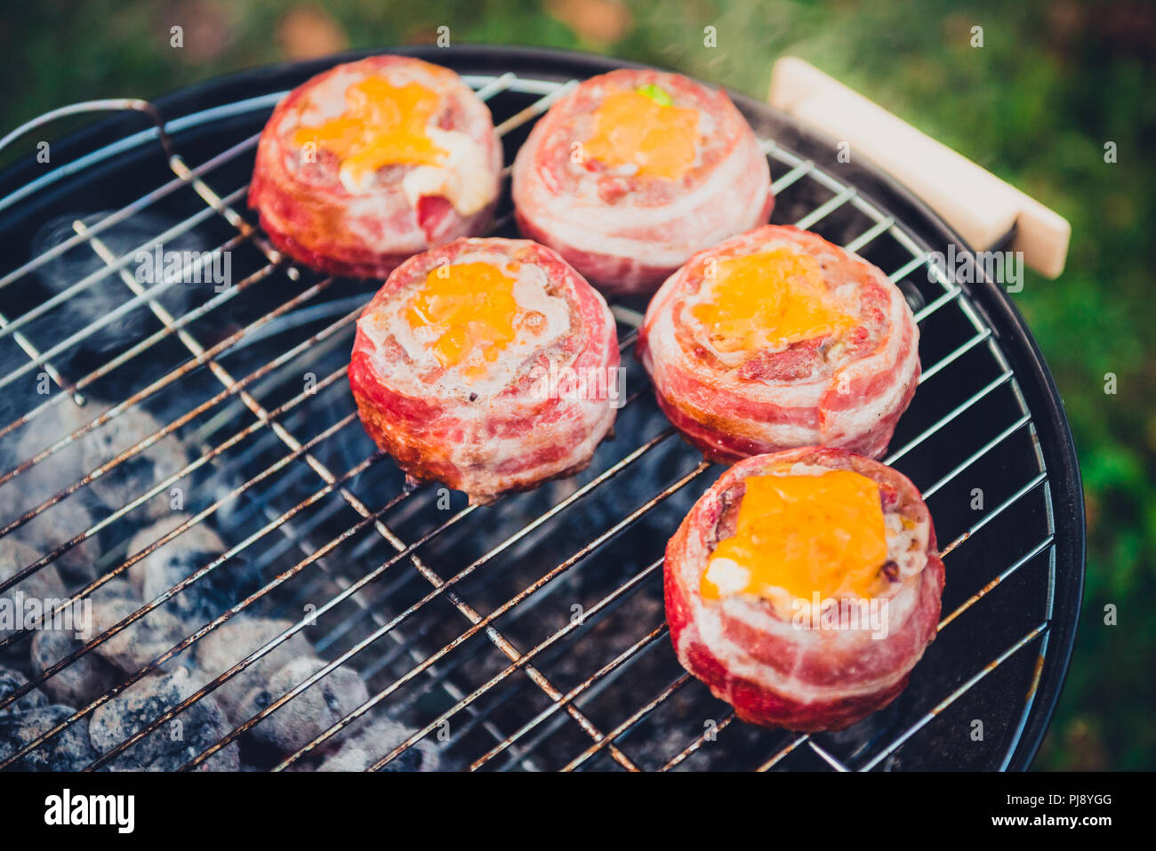 Rendendo fatta in casa birra può Bacon gli hamburger sul grill barbecue. La preparazione di polpette ripiene, avvolto in pancetta e grigliare sul calore indiretta nella natura a bac Foto Stock