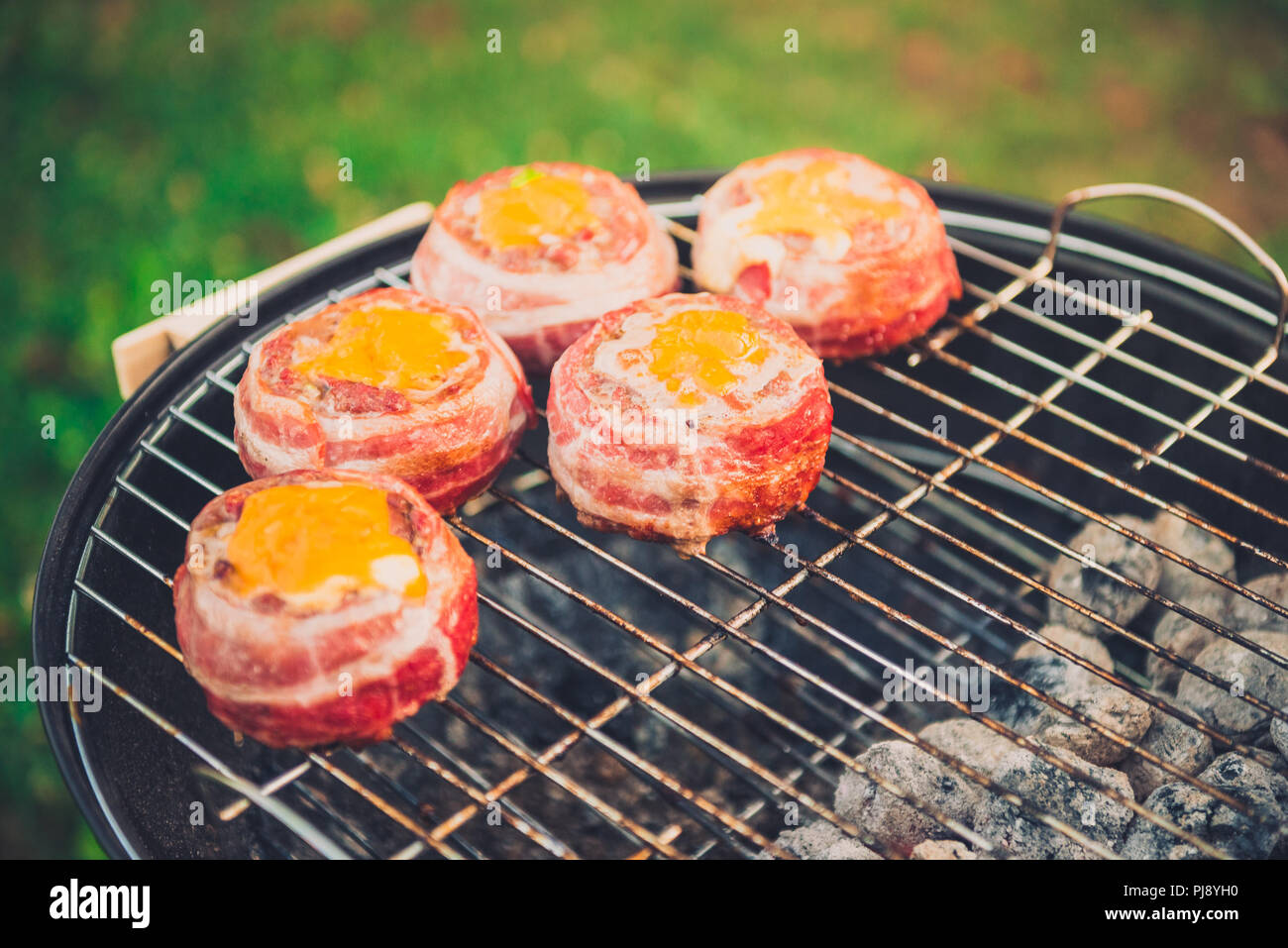 Rendendo fatta in casa birra può Bacon gli hamburger sul grill barbecue. La preparazione di polpette ripiene, avvolto in pancetta e grigliare sul calore indiretta nella natura a bac Foto Stock