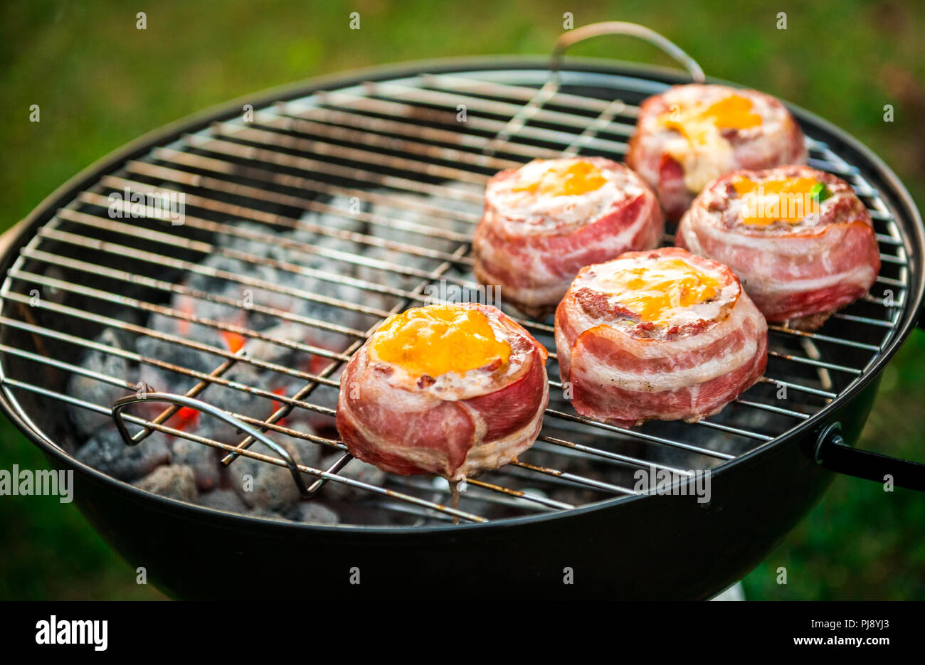 Rendendo fatta in casa birra può Bacon gli hamburger sul grill barbecue. La preparazione di polpette ripiene, avvolto in pancetta e grigliare sul calore indiretta nella natura a bac Foto Stock