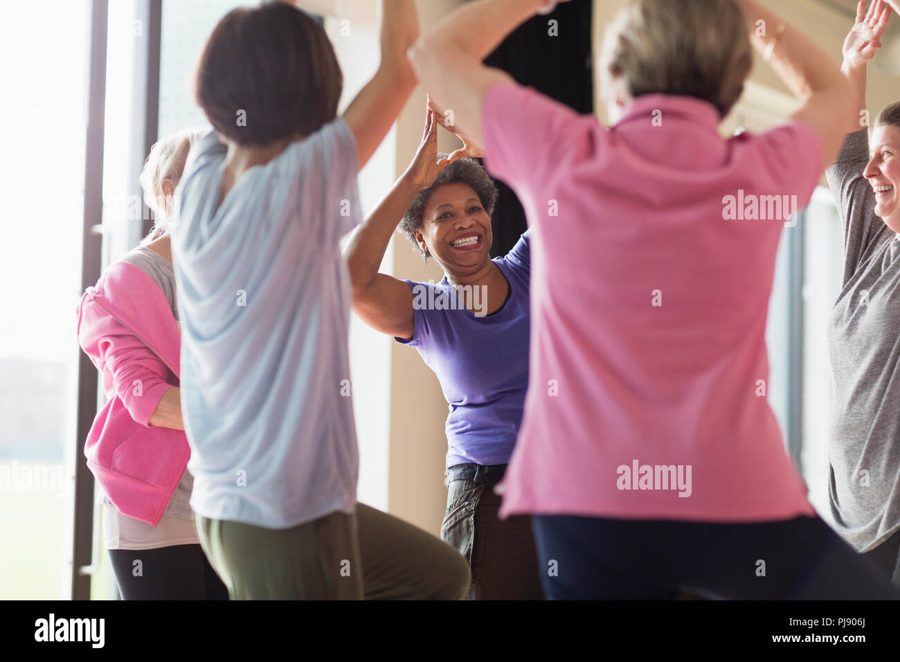 Sorridente senior attiva donna esercita la pratica dello yoga posa ad albero Foto Stock