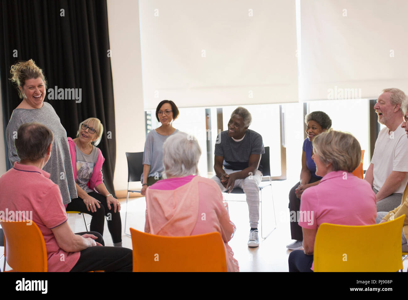 Ridendo active seniors riuniti in cerchio nel centro comunitario Foto Stock
