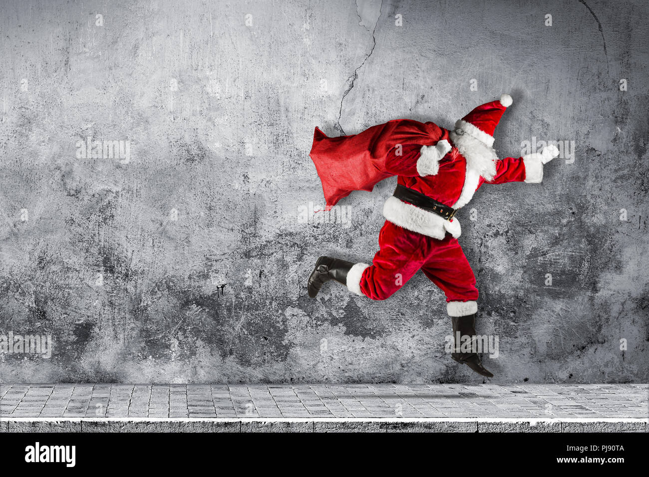 Fine santa claus in fretta con tradizionale rosso bianco costume e una borsa piena di regali in esecuzione jumping astratta Natale divertente xmas backgro concrete Foto Stock