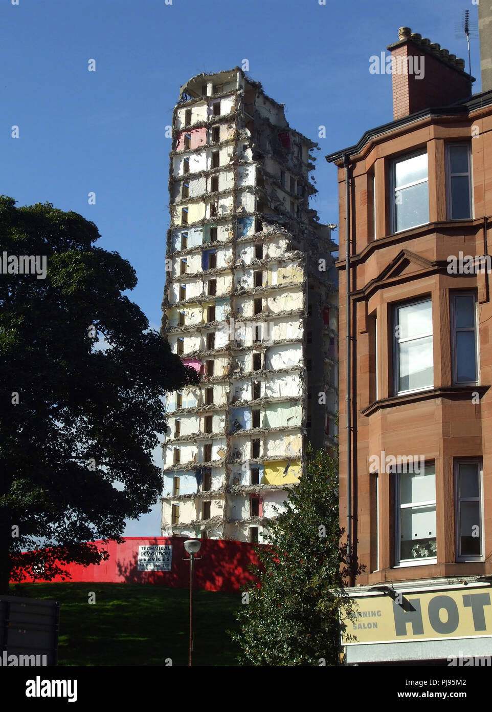 Un parzialmente demolito alto edificio di appartamenti in piedi accanto a una pietra arenaria rossa casamento in Glasgow. Foto Stock