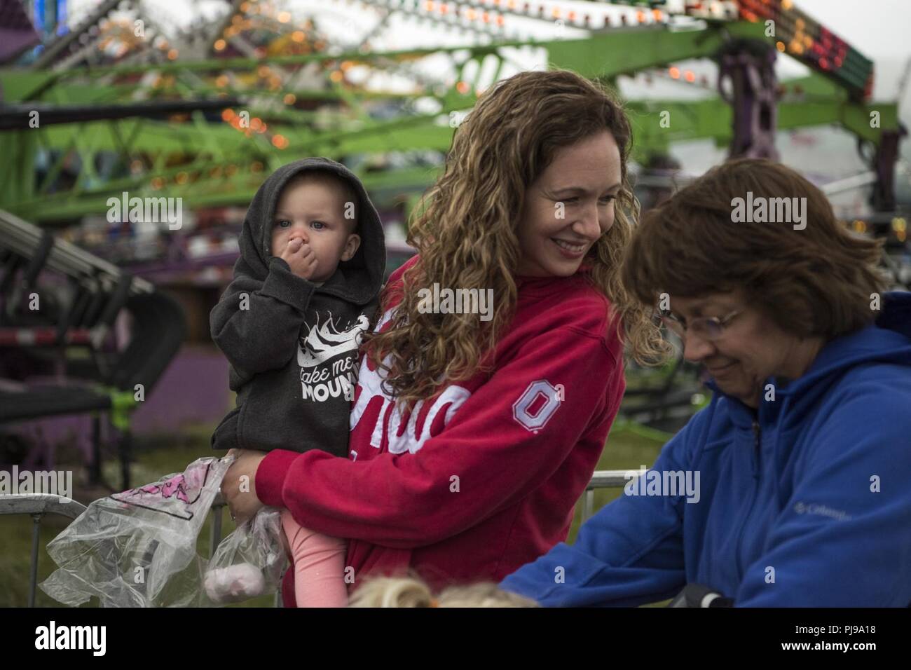 Hailey, 1, è detenuto dalla sua zia, Jama Singh, come lei mangia la caramella di cotone durante la terza edizione Summer Fest ospitato dal 673d forza squadrone di supporto a base comune Elmendorf-Richardson, Alaska, Luglio 8, 2018. La manifestazione è stata aperta a chiunque con accesso di base e offerto gratuitamente attività come gite di carnevale, uno zoo di animali domestici, face painting una bungee trampolino e giochi di carnevale. Foto Stock