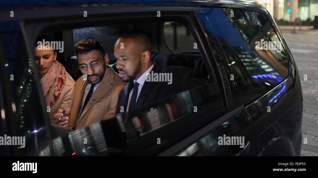 La gente di affari nel sedile posteriore di un taxi crowdsourced di notte Foto Stock