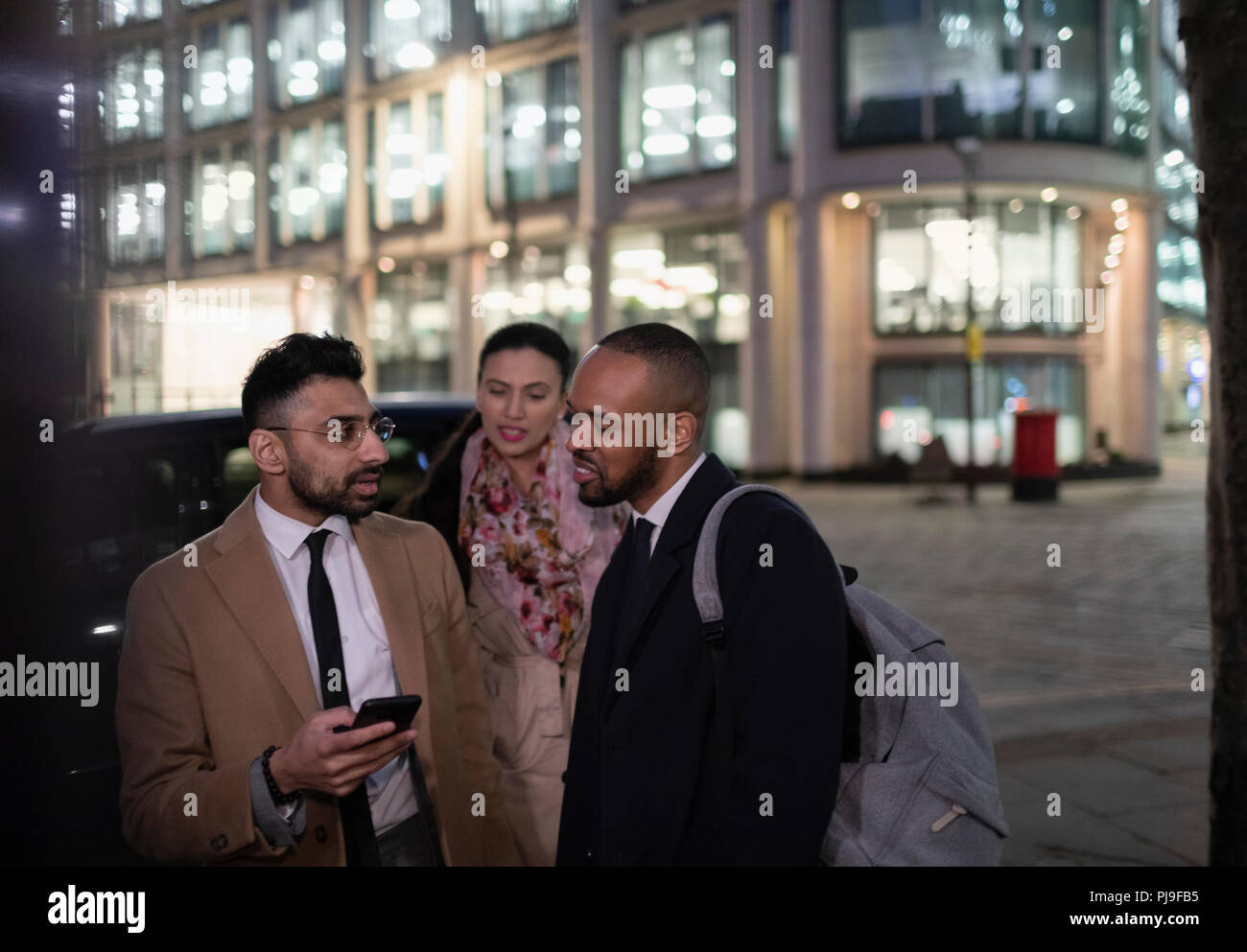 La gente di affari con smart phone parlando sulla via della città di notte Foto Stock