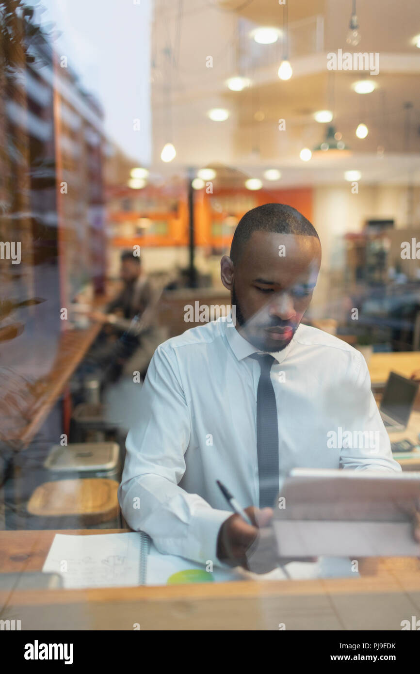 Imprenditore con tavoletta digitale, lavorando nella finestra cafe Foto Stock