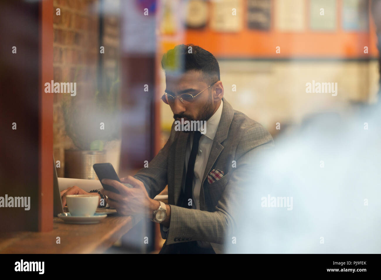 Imprenditore utilizzando smart phone, lavorando in cafe Foto Stock