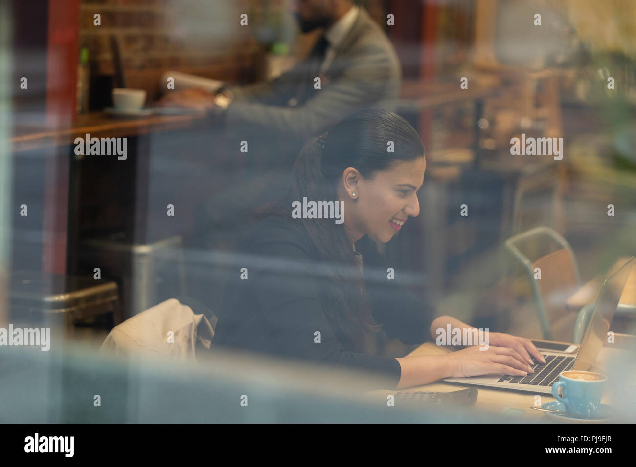 Sorridente imprenditrice lavora al computer portatile in cafe Foto Stock