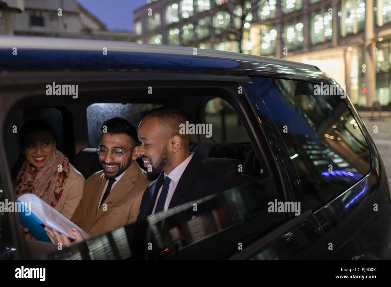 La gente di affari la revisione di documenti cartacei in crowdsourced taxi di notte Foto Stock