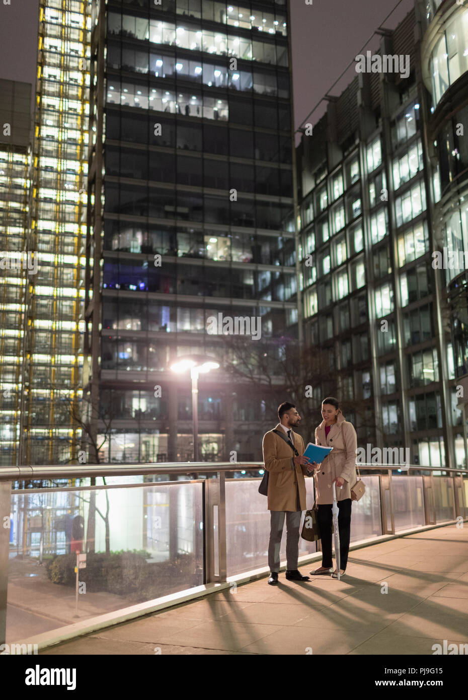 Imprenditori documenti di discussione sulle questioni urbane ponte pedonale di notte Foto Stock