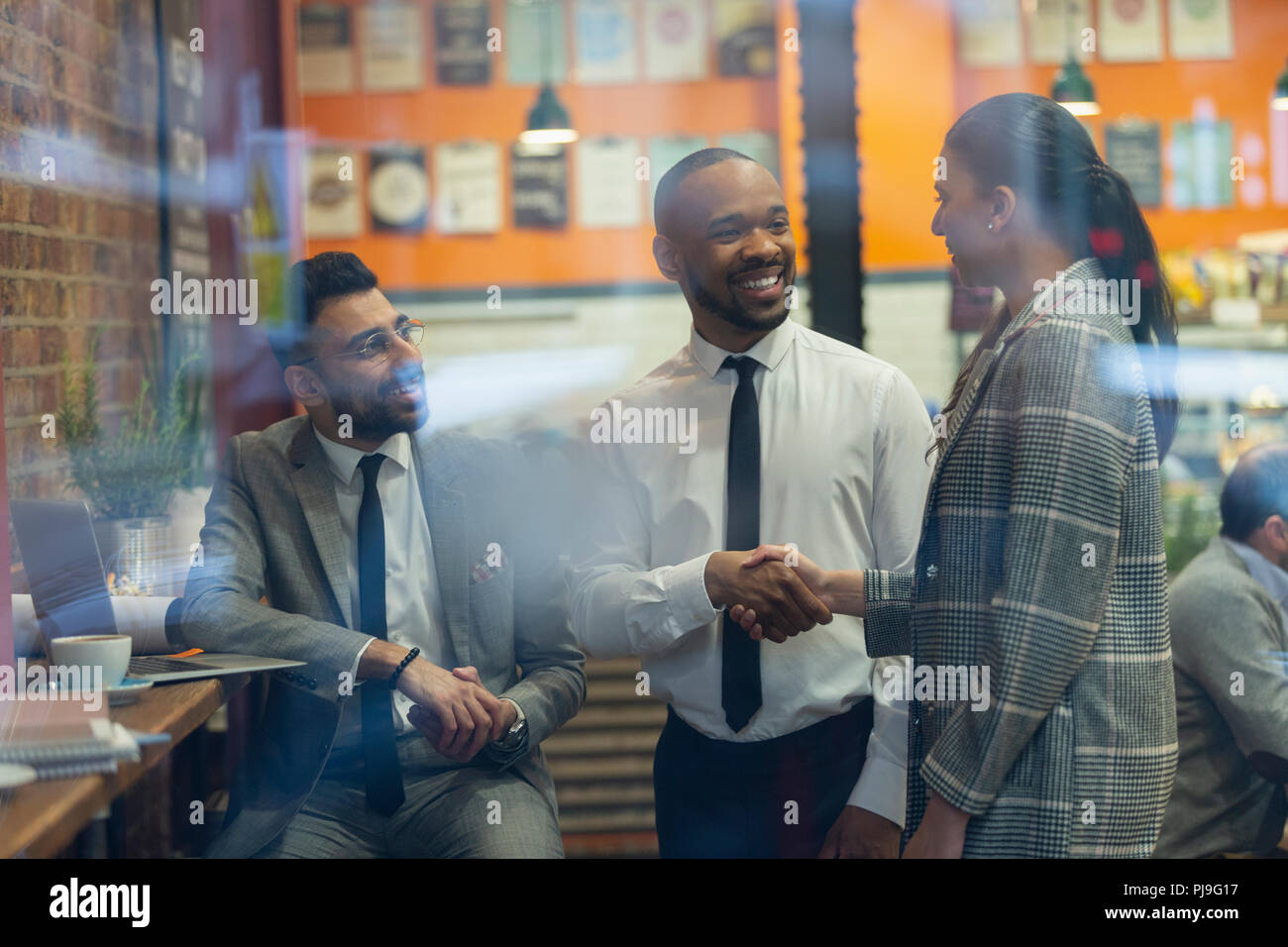 Sorridente la gente di affari di handshaking cafe Foto Stock