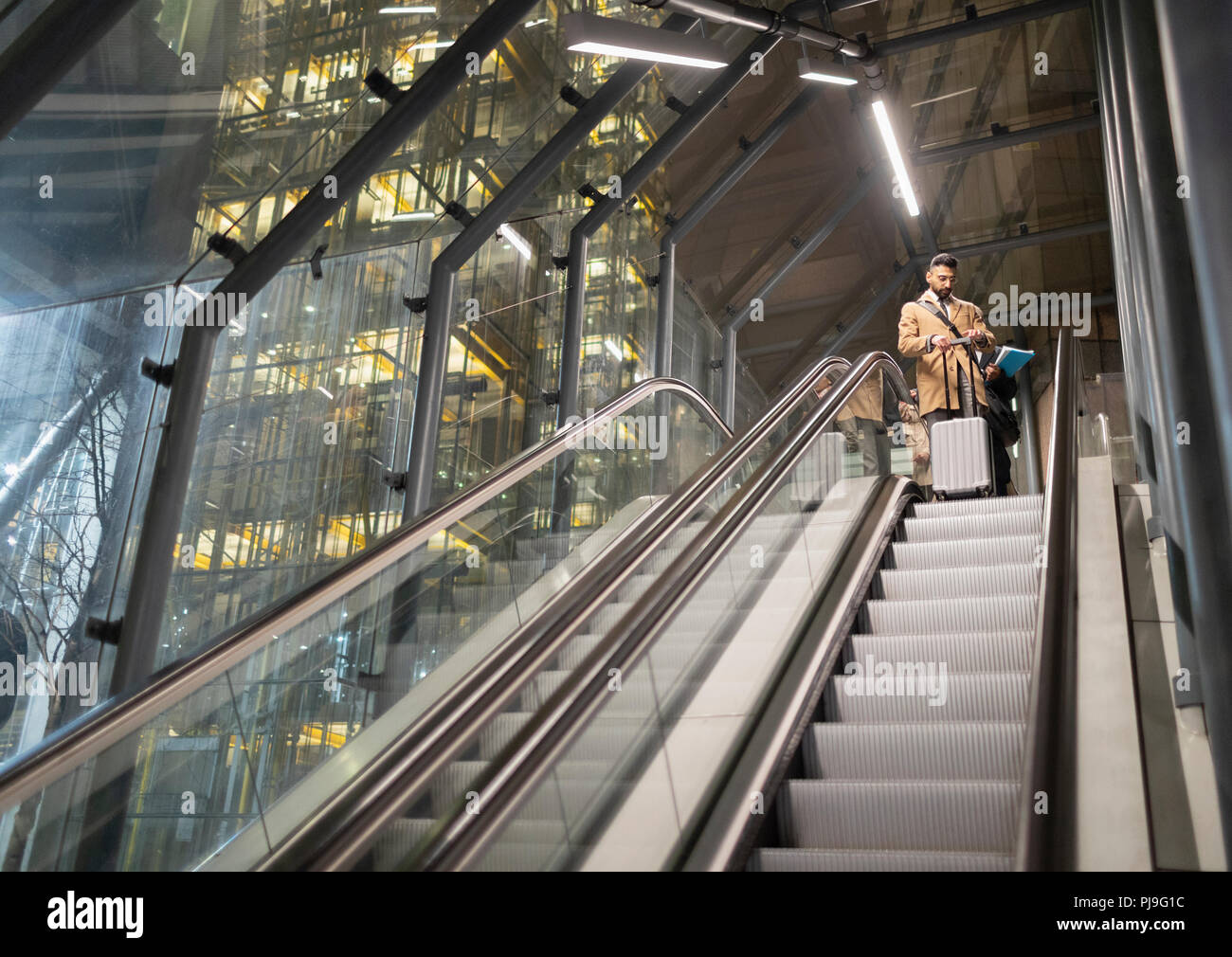 Imprenditore con valigia su urban escalator Foto Stock