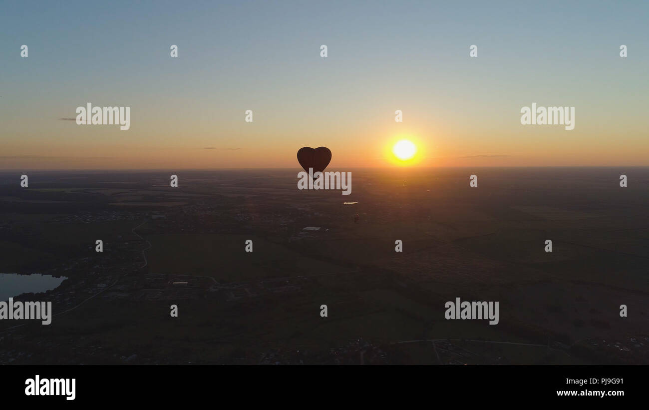 Vista aerea Forma mongolfiera cuore nel cielo sopra il campo in campagna, bellissimo cielo e al tramonto. Aerostato volare su campagna. Foto Stock
