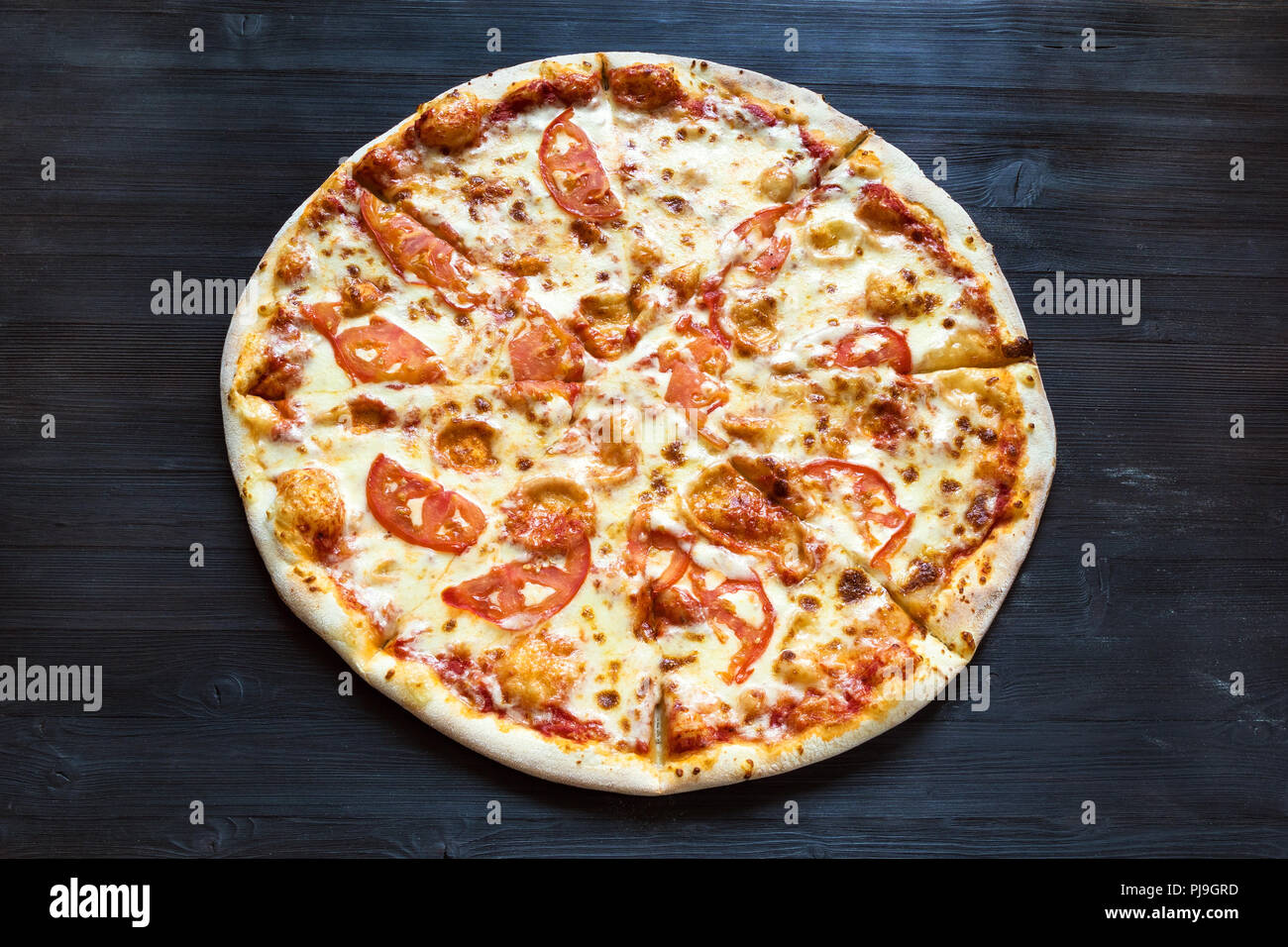 La pizza italiana con formaggio e pomodori in legno marrone scuro board Foto Stock