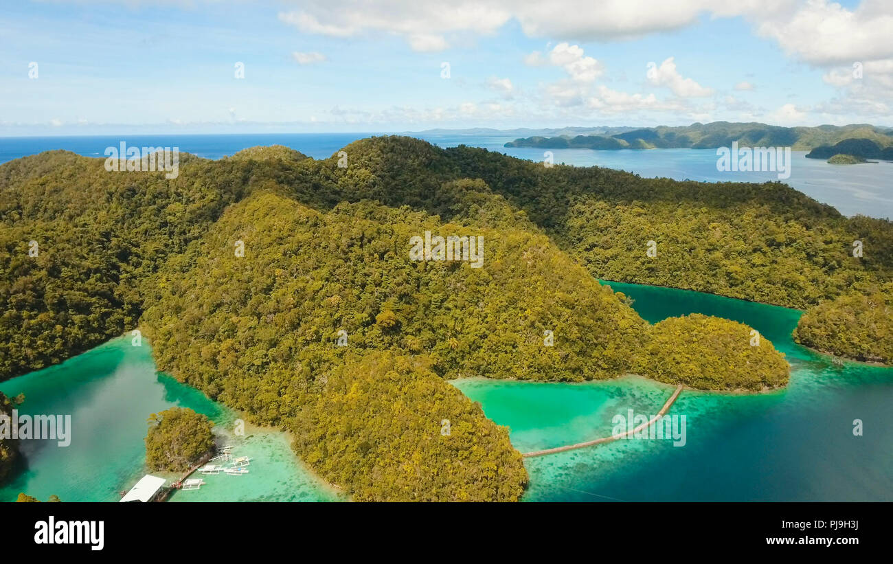 Vista aerea: spiaggia, isola tropicale, Baia Mare e laguna, Siargao. Paesaggio tropicale hill, nuvole e montagne rocce con la foresta pluviale. Acque azzurre della laguna. Paesaggio Shore Bay. Concetto di viaggio. Foto Stock