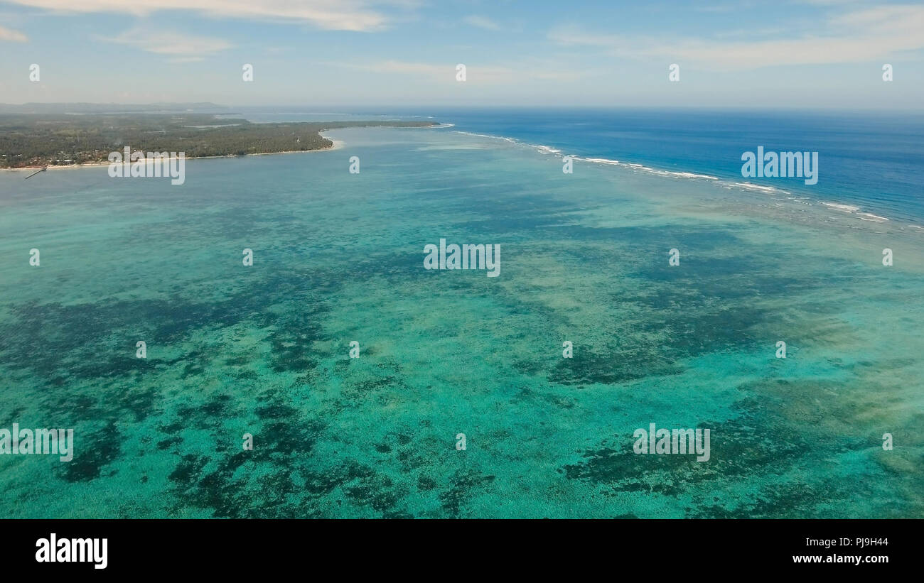 Costa dell'isola tropicale Siargao con le montagne e la foresta pluviale su uno sfondo di oceano con grandi onde. Vista aerea: mare e l'isola tropicale con rocce, la spiaggia e le onde. Seascape: sky, nuvole oceano. Filippine. Concetto di viaggio. Foto Stock