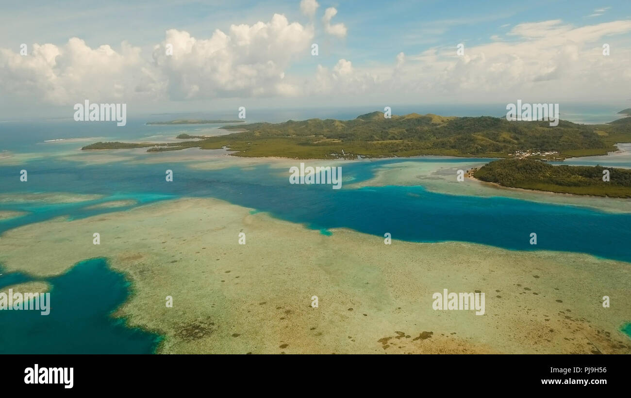 Vista aerea: spiaggia, isola tropicale, Baia Mare e laguna, Siargao. Paesaggio tropicale hill, nuvole e montagne rocce con la foresta pluviale. Acque azzurre della laguna. Paesaggio Shore Bay. Seascape. Concetto di viaggio. Foto Stock