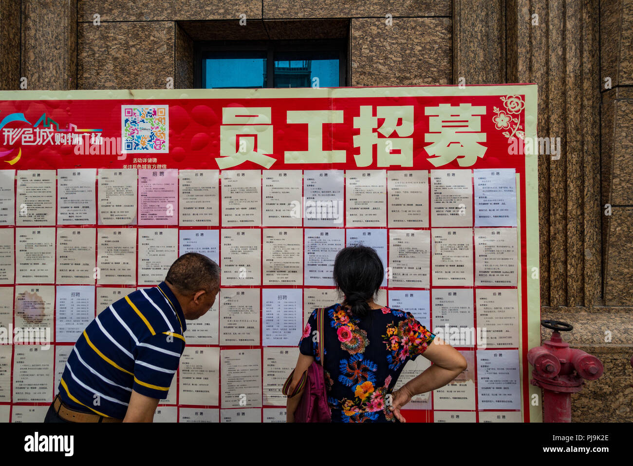 Invecchiamento in cerca di lavoro guardando i lavori bulletin board di Shenzhen in Cina Foto Stock