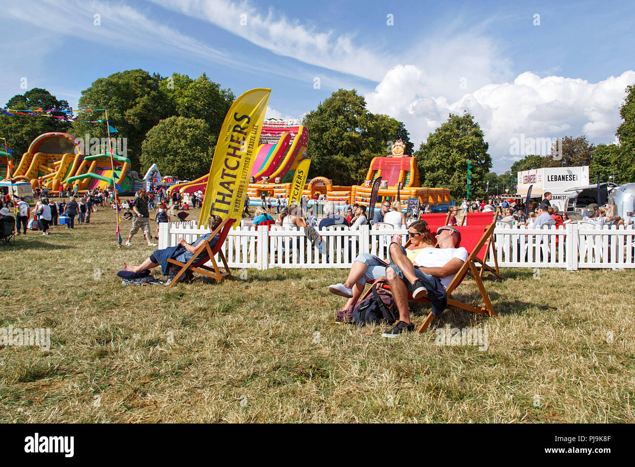 Bristol, Regno Unito: Agosto 09, 2018: turisti rilassarsi con un rinfrescante Thatchers sidro da una concessione di stand a Bristol International Balloon Fiesta. Foto Stock