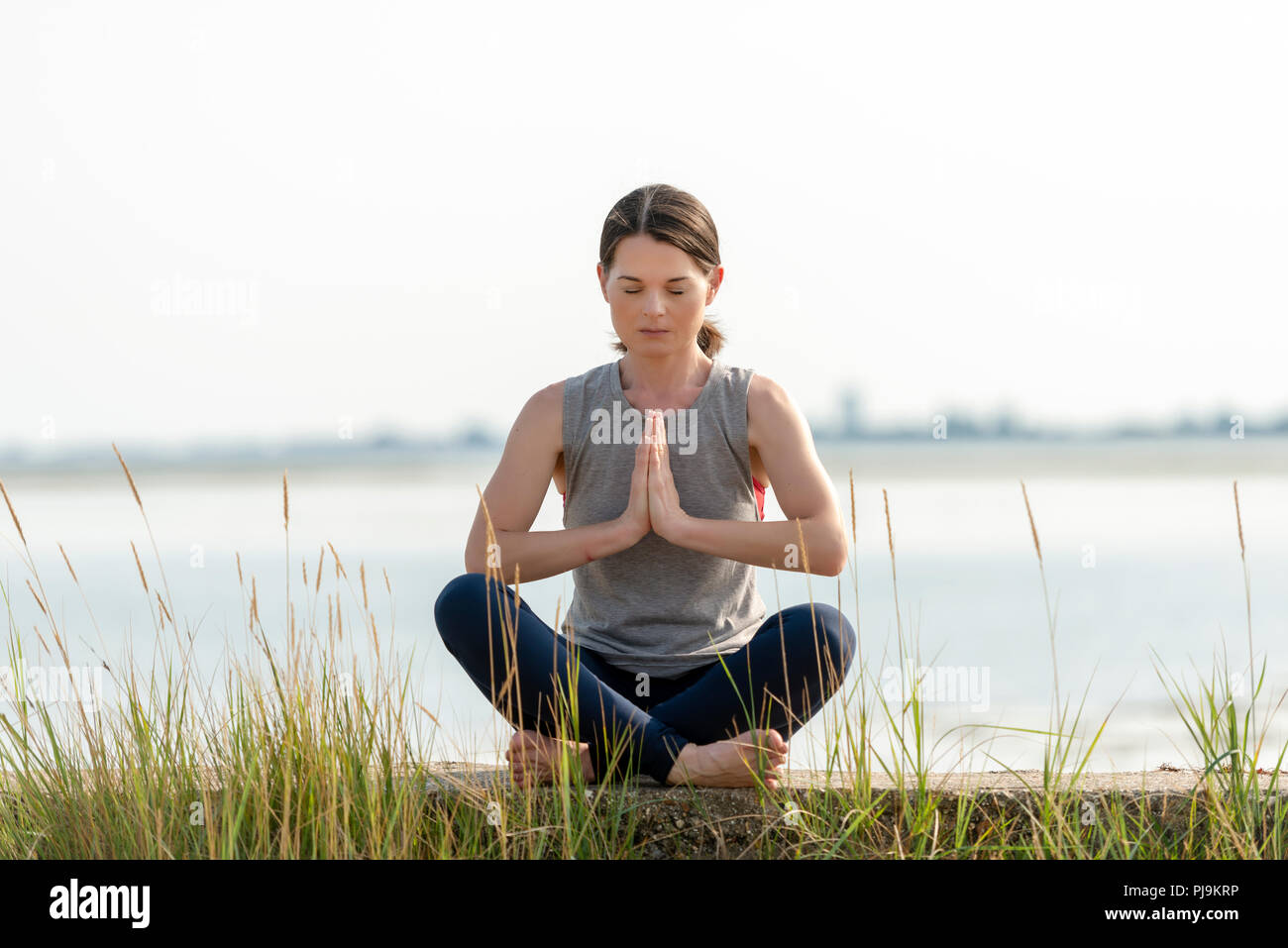 Donna seduta gambe incrociate e la meditazione Foto Stock